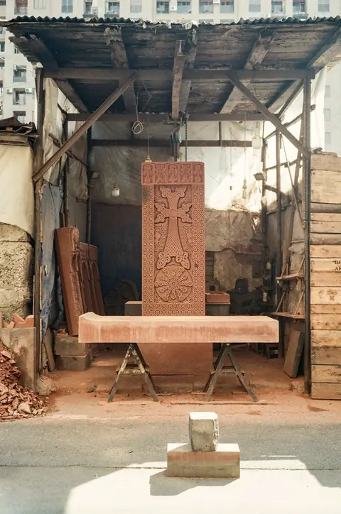 Atelier de taille sous abri, stèle de pierre dressée, établi et outils