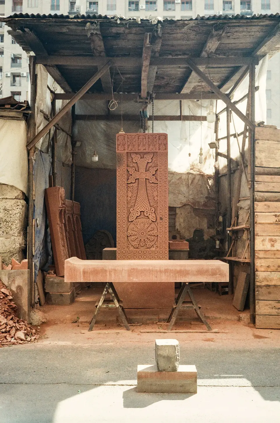 Atelier de taille sous abri, stèle de pierre dressée, établi et outils