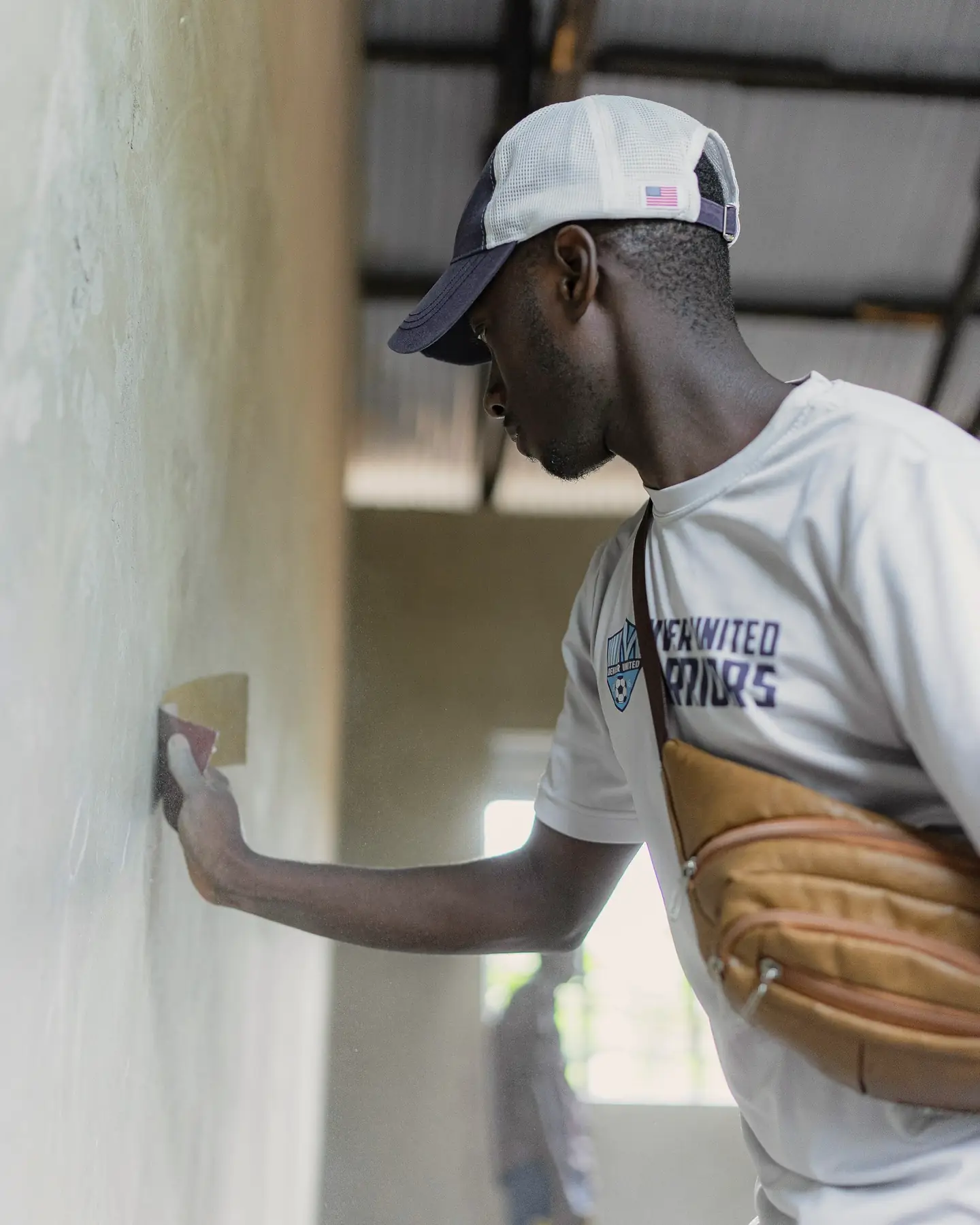 Artisan qui lisse un enduit sur un mur clair, lame à la main