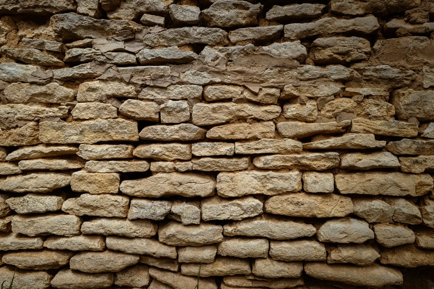 Mur de pierre calcaire blonde monté en assises irrégulières, joints de mortier clair
