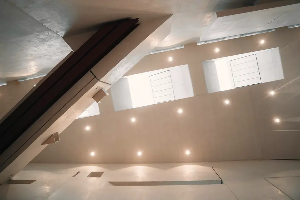 Plafond lisse sous rampant, ponctué de spots encastrés et de fenêtres de toit